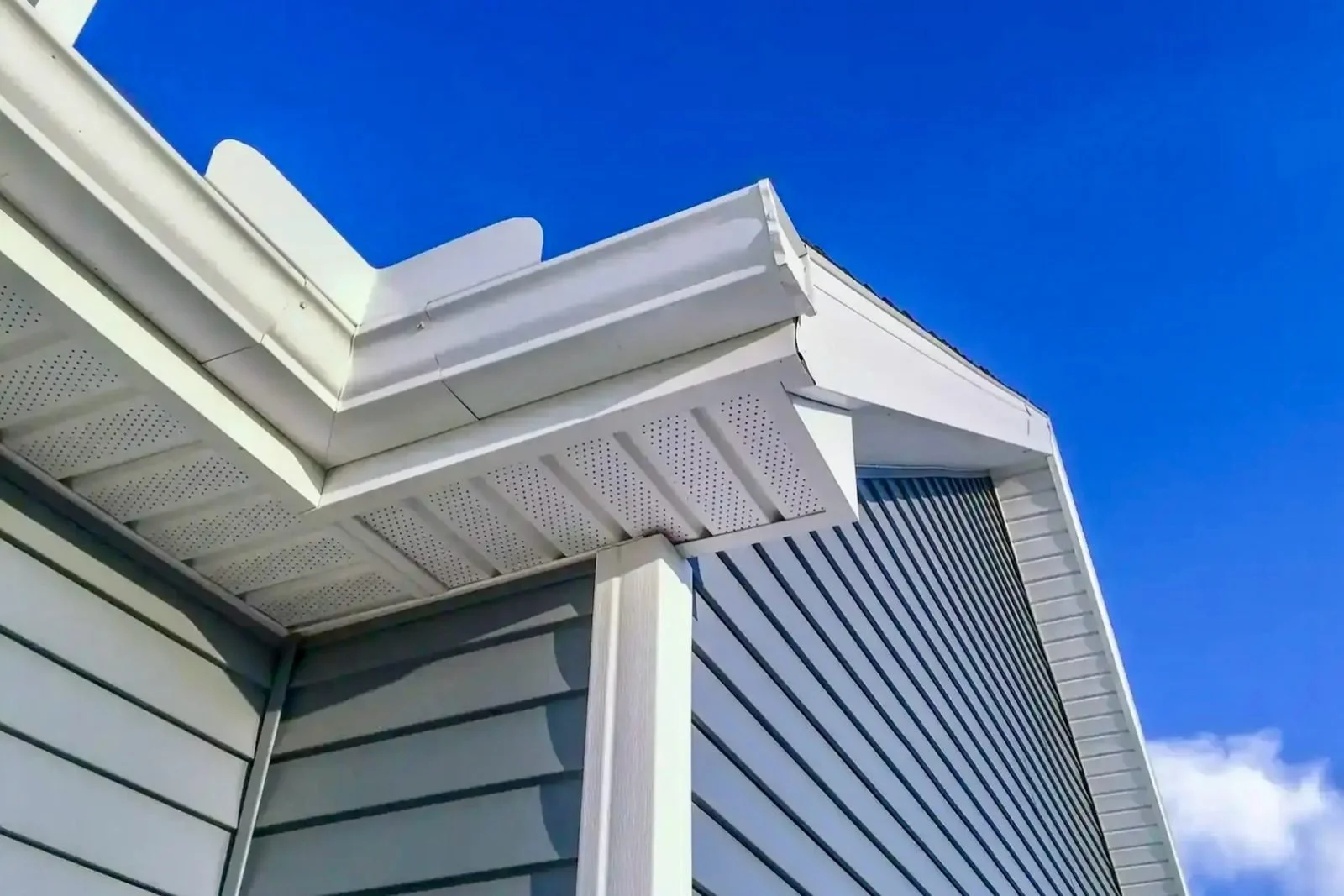 Close-up of new white seamless gutters and vented soffit installed on a residential home in Sarasota, FL by Barrier Builders.
